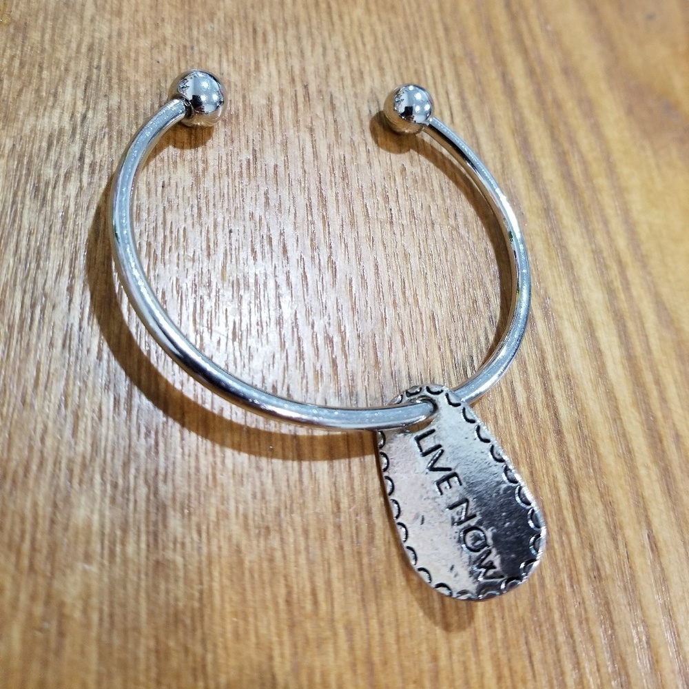 Silver colored bangle with "live now" charm